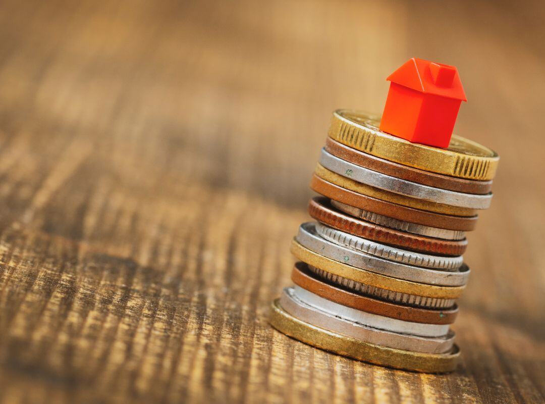 Modellhaus steht auf einem Stapel aus Münzen. Nachhaltige Immobilien.